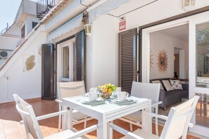 A dining area with a table set for two, a bowl of fruit, and a sign indicating a fire alarm.