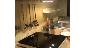 A modern kitchen with a built-in induction cooktop, a stainless steel sink, and hanging utensils. - CENTRAL APARTMENT (BARI)