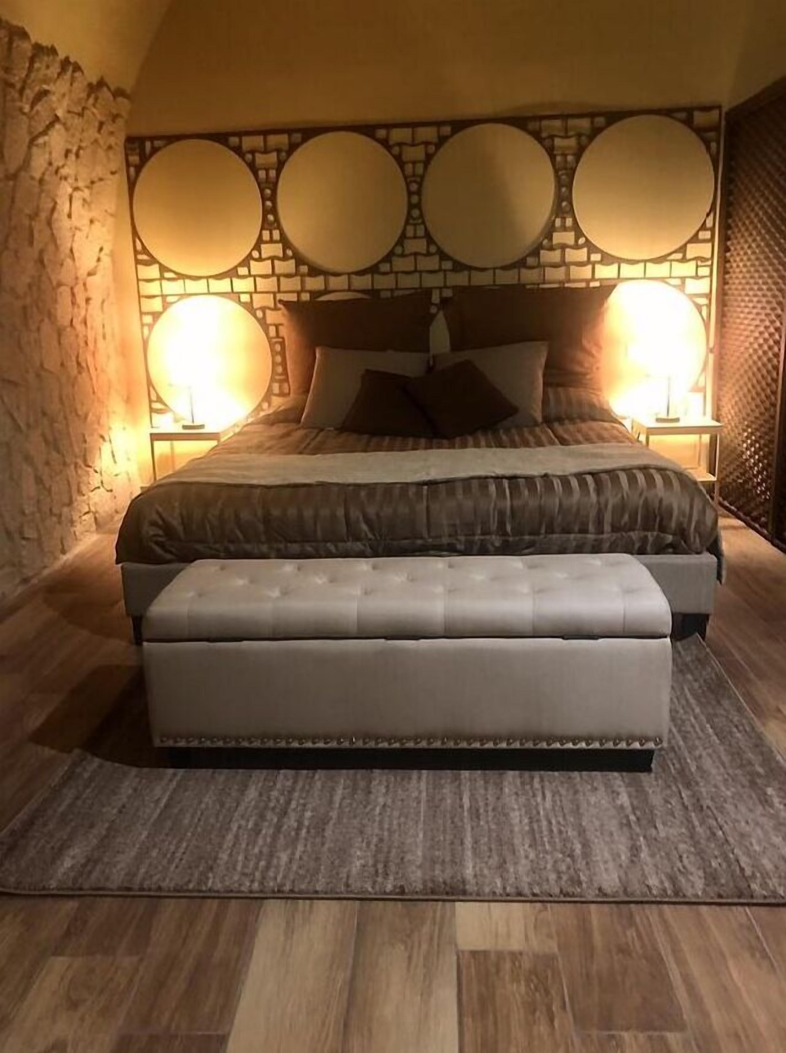 Een slaapkamer met een groot bed, een bijpassende bank en twee wandlampen.