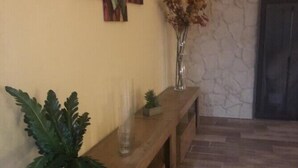 A wooden bench with a potted plant and a vase of dried flowers against a wall with abstract art. - CENTRAL APARTMENT (BARI)