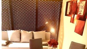 A dining area with a glass table set for four, surrounded by chairs. There is a sofa in the background with cushions. - CENTRAL APARTMENT (BARI)