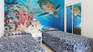 Ein Schlafzimmer mit zwei Betten, einem Nachttisch und einem Wandgemälde mit einer Schildkröte.