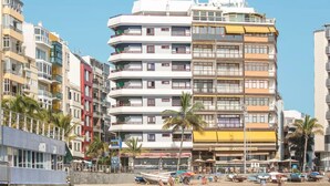 Un hôtel à plusieurs étages doté de balcons, situé en bord de mer et comprenant un restaurant au rez-de-chaussée.