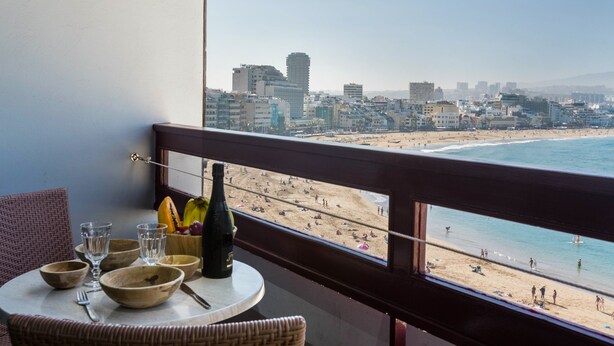 A balcony with a table, chairs, and a view of a beach and cityscape. - Vacation Rental “Studio 50” with Sea View, Terrace & Wi-Fi (Las Palmas de Gran Canari)