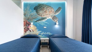 Una stanza con due letti, un murale raffigurante una tartaruga marina e un comodino.