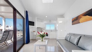 Un soggiorno moderno con un divano, un tavolo con fiori e vista attraverso una porta in vetro.