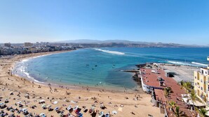Paesaggio costiero con spiaggia, edifici e cielo sereno.