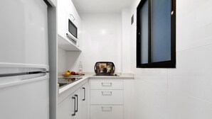 Una cucina compatta con mobili bianchi, un forno a microonde e una macchina da caffè.