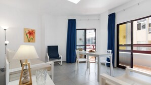Una camera d'hotel moderna con zona pranzo, una sedia, una lampada e vista sull'esterno.
