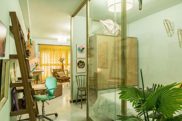 Une pièce comprenant un lit, un bureau, une chaise et une cloison en verre.