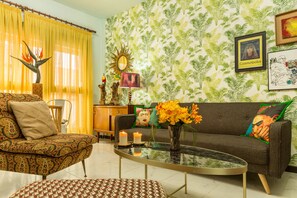 Un salon avec un canapé à motifs, une table basse et une plante décorative.