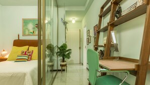A bedroom with a bed, bedside table, lamp, and a green chair.