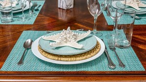 Una mesa de comedor dispuesta con un centro de mesa decorativo, platos, cubiertos y cristalería.