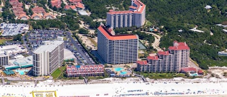 Ett hotellkomplex vid kusten med flera höga byggnader, en strand och en parkeringsplats.