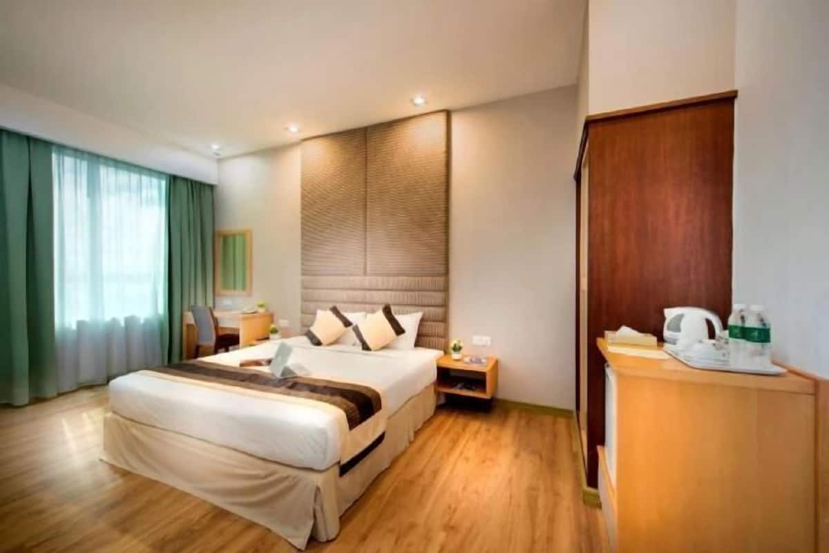Hotelkamer met een groot bed, houten vloer, bureau met stoel, nachtkastje en een kledingkast.