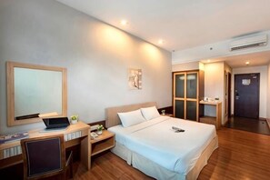 Una habitación de hotel con cama, escritorio, silla y puerta.