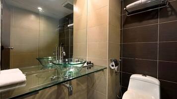 A modern bathroom with a glass sink, a toilet, and a towel rack.