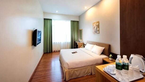 A hotel room with a bed, bedside table, TV, and a window with curtains. - Kingwood Hotel Mukah (Mukah)