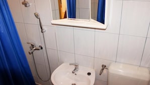 A bathroom with a white sink, a handheld showerhead, a toilet, and blue curtains. - Room Lazareti (Dubrovnik)