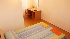 A small, neatly arranged bedroom with a single bed, a wooden desk, and a chair. - Room Lazareti (Dubrovnik)