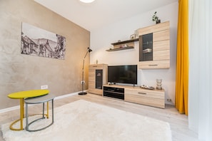 Deluxe studio suite | Woonruimte | Een 80-cm flatscreentelevisie met kabelzenders en een televisie