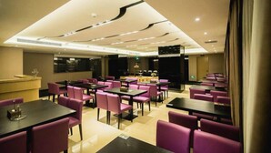 A restaurant with multiple tables and chairs, a reception desk, and a modern ceiling design. - Lavande Hotel (Jiangmen)