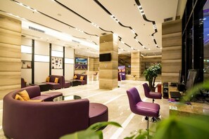 A modern lobby with seating areas, a reception desk, and a large screen. - Lavande Hotel (Jiangmen)