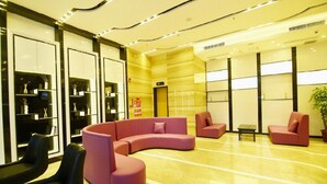 A modern lobby with a curved pink sofa, black chairs, and a small table. - Lavande Hotel (Jiangmen)