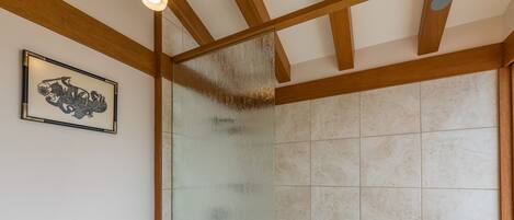 A bathroom with a glass shower enclosure, a toilet, and a framed artwork on the wall.