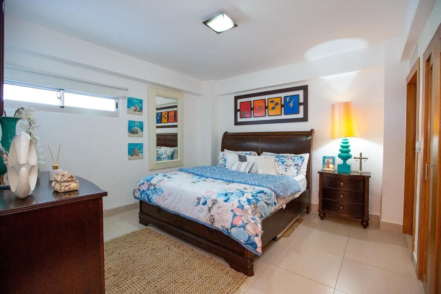 Ein Schlafzimmer mit Bett, Nachttisch, Lampe, Kommode und Wandbild.