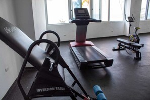 Et fitnesscenter med vægtopmøbel, løbebånd og motionscykel.