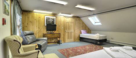 A bedroom with a loft bed, a desk, a chair, a television, and a window.
