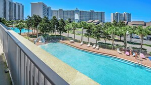 Un hotel con piscina, palmeras y edificios altos al fondo.