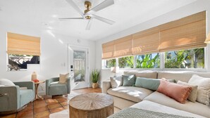 A spacious living room with a large sofa, two armchairs, a wooden coffee table, and a ceiling fan. - Plumeria Villa by Beach Boutique Rentals (Holmes Beach)