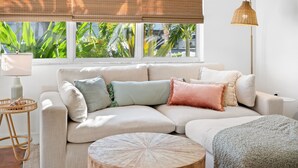 A modern living room with a sectional sofa, a round wooden coffee table, and a floor lamp. - Plumeria Villa by Beach Boutique Rentals (Holmes Beach)