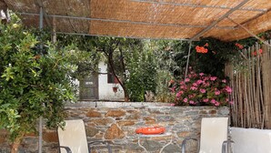 A covered outdoor seating area with stone walls and metal chairs. - Paradise Found - A Greek Retreat With The View (Skopelos)