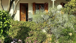 A rustic house with a tiled roof, surrounded by a lush garden with various plants and flowers. - Paradise Found - A Greek Retreat With The View (Skopelos)