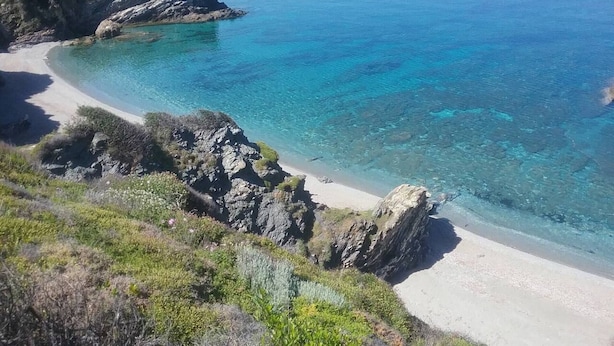 A coastal landscape with a clear beach, rocky outcrops, and a view of the sea. - Paradise Found - A Greek Retreat With The View (Skopelos)