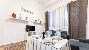 A dining area with a table set for four, a television, and a sofa.