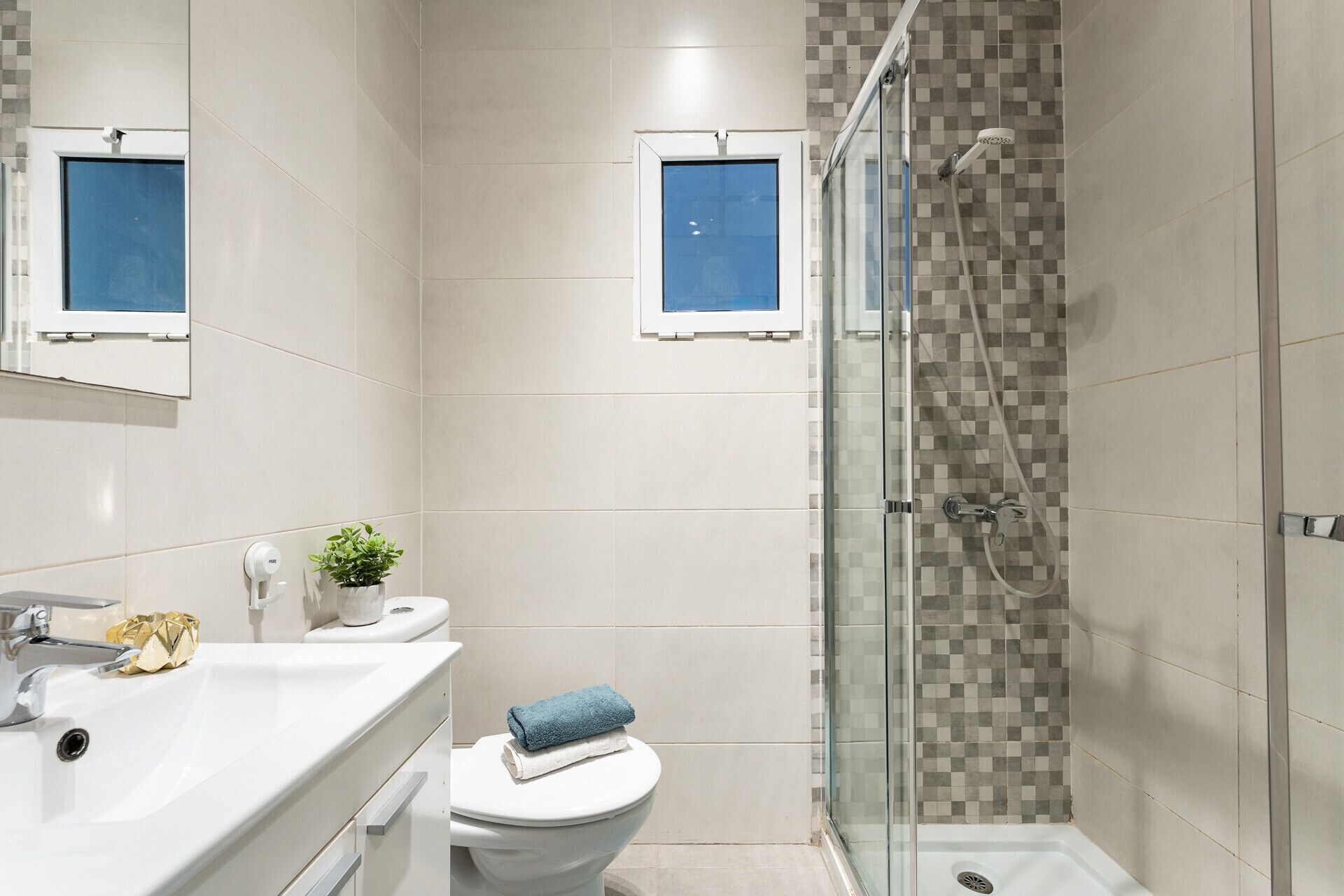 A modern bathroom with a shower, toilet, and sink.