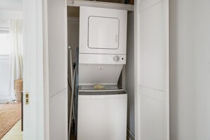 A compact laundry room with a washing machine and dryer stacked vertically. - Blithely Baroque (Atlanta)