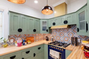 A kitchen with teal cabinets, a patterned backsplash, a wooden countertop, and a blue stove.