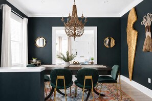 A dining area with a chandelier, two chairs, a table, and a large mirror.