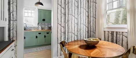 Un comedor con una mesa redonda de madera, sillas doradas y un cuenco sobre la mesa.