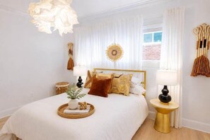 Une chambre à coucher avec un grand lit, des lampes de chevet, une décoration murale et une fenêtre avec des rideaux.