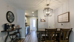 Una cucina moderna con macchina da caffè, orologio e zona pranzo con sedie e tavolo di legno.