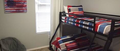 A bunk bed with a British flag design, a gray bean bag chair, and an American flag painting on the wall.