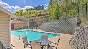 Una piscina con una parete in pietra e vista su un edificio blu sullo sfondo.