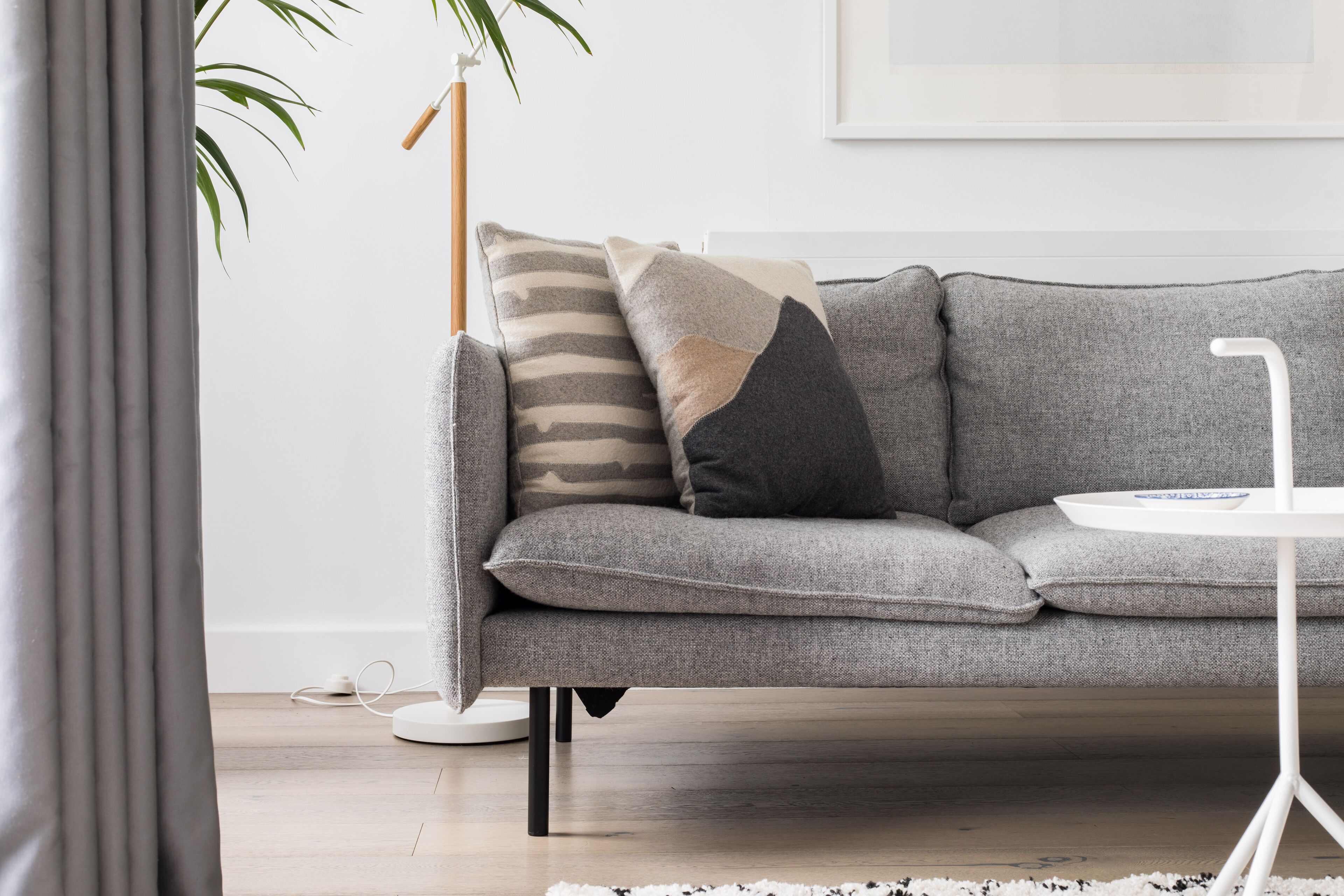 Un salón moderno con un sofá gris, una mesa de centro blanca y una planta.
