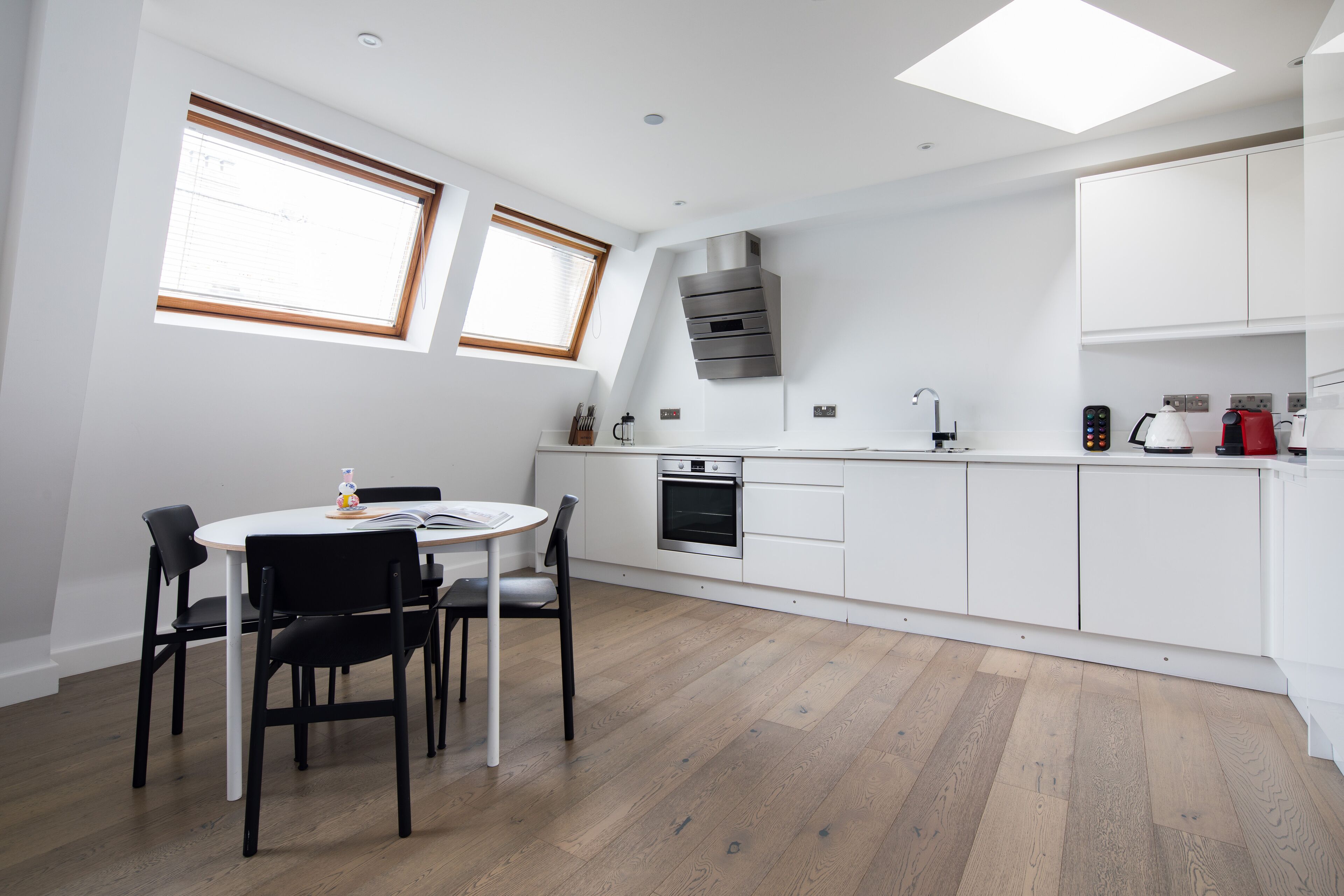 A modern kitchen with white cabinets, a built-in oven, and a window above the sink.